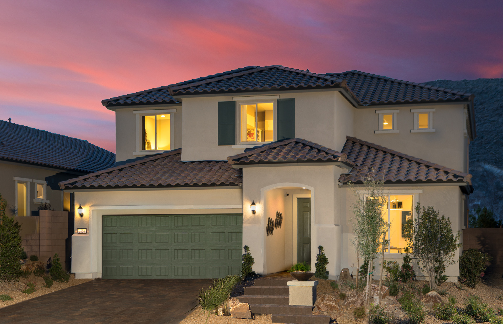 Luxurious two-story home with terracotta roof and landscaped front yard at dusk.